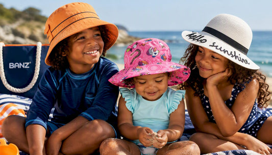 Three kids on a family beach day in BANZ sun hats