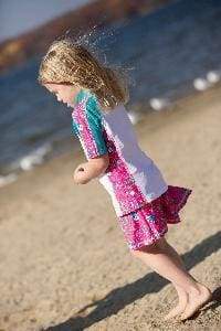 young girl at beach wears banz short sleeve rash top and swim skirt
