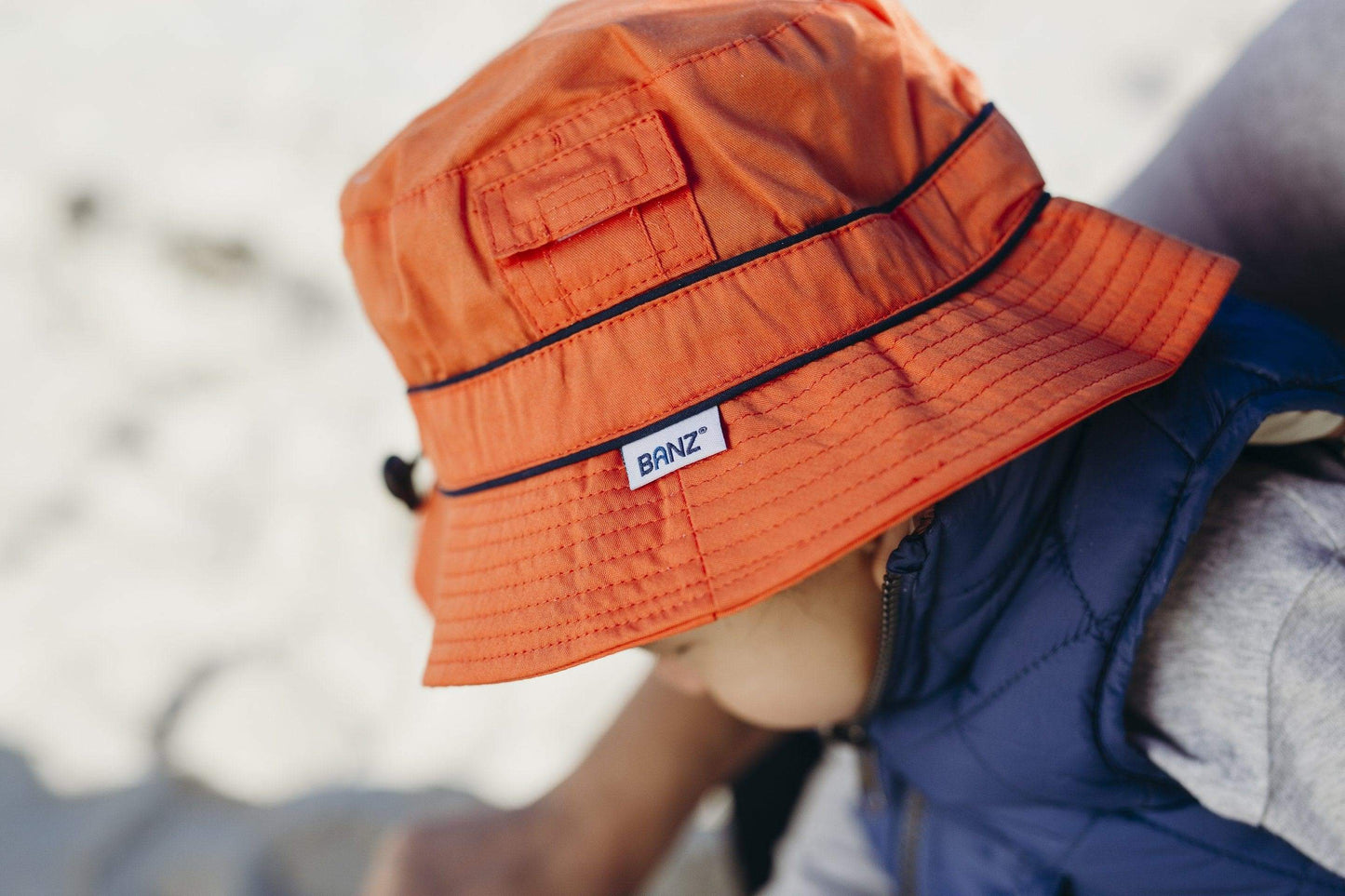 young child wears sun hat with pocket, pocket detail and banz tag can be seen close up