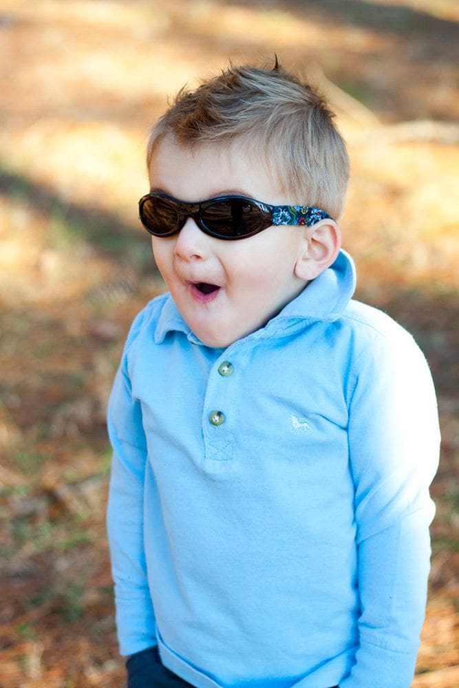a young child looks surprised in the park wearing banz wrap around sunglasses