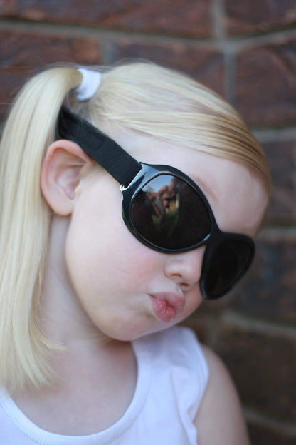 a young girl purses her lips at the camera in retro banz wrap around sunglasses